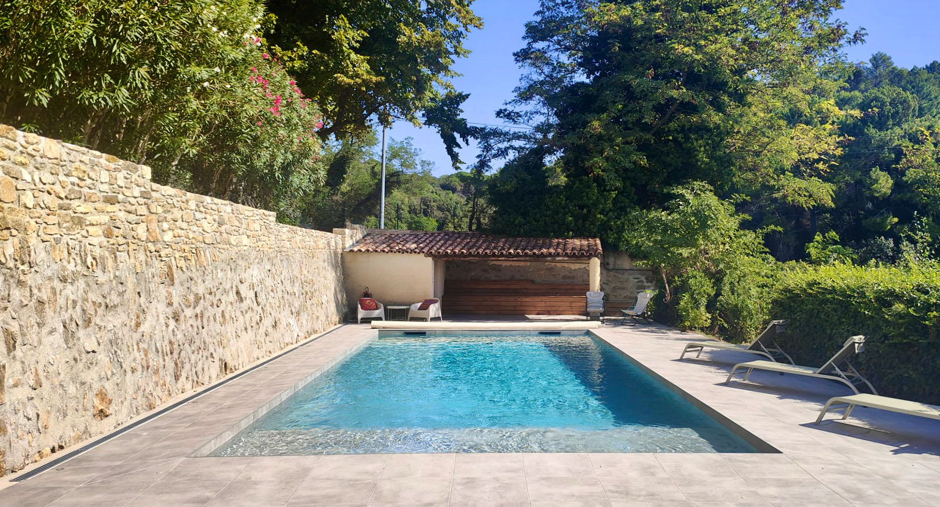 Piscine de La Petite Blanchardière entourée de murs en pierre et de végétation