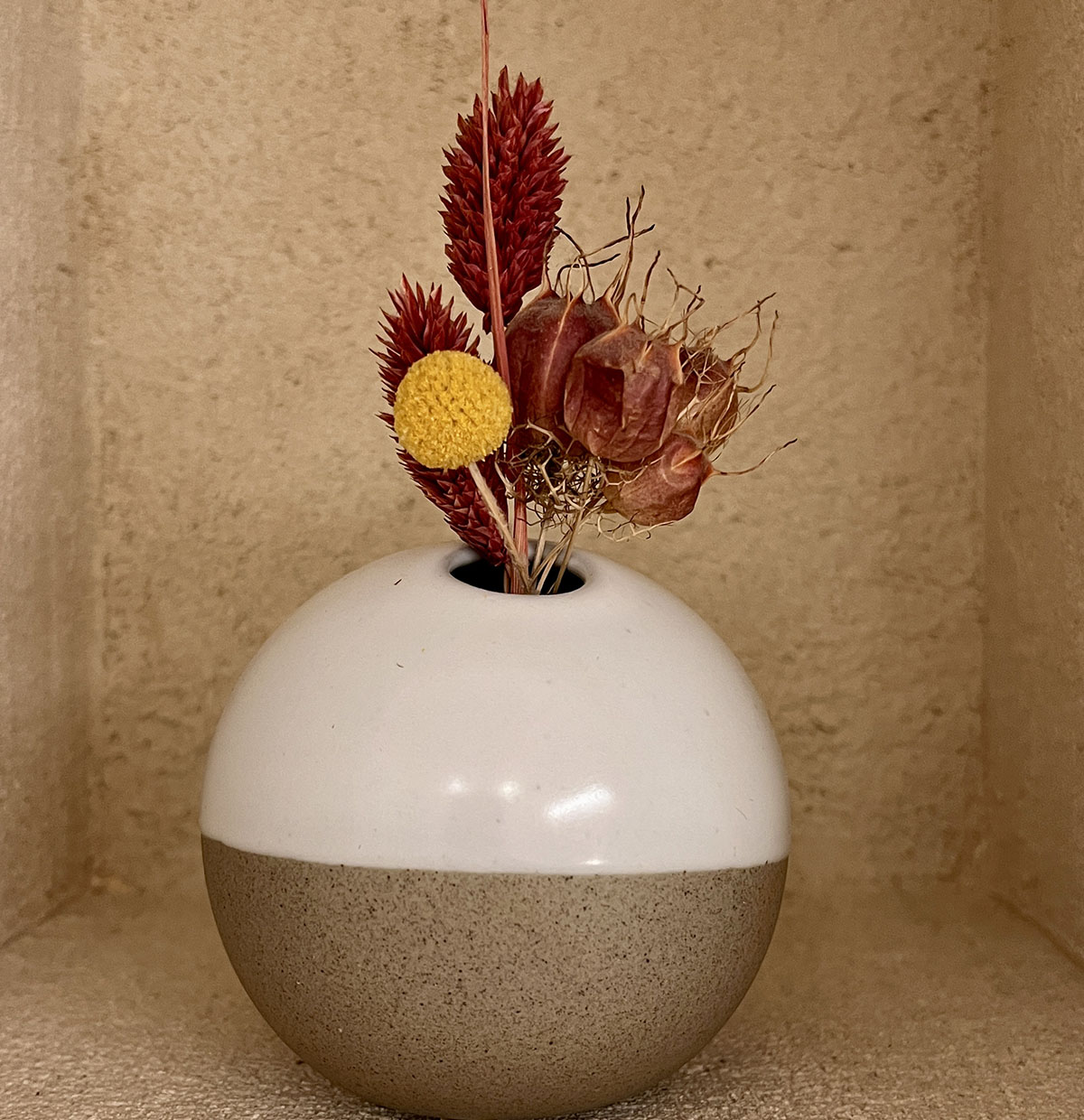 Bouquet de fleurs séchées rouges et jaunes dans un vase en céramique au gîte La Réserve