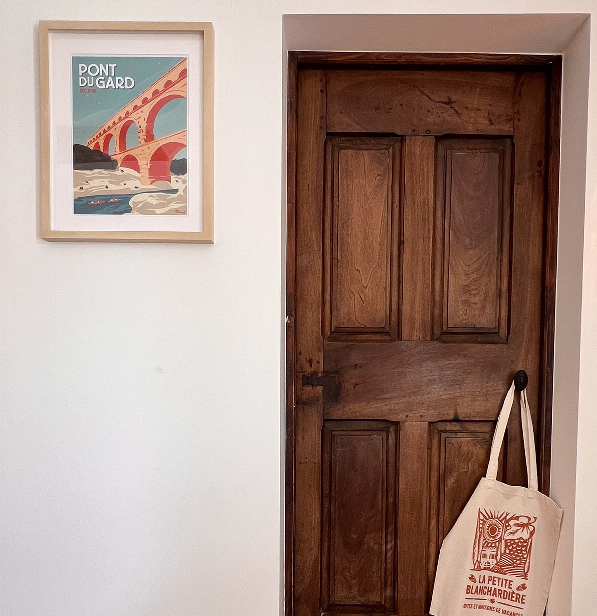 Porte ancienne en bois, affiche du Pont du Gard et sac en toile La Petite Blanchardière dans le gîte La Réserve
