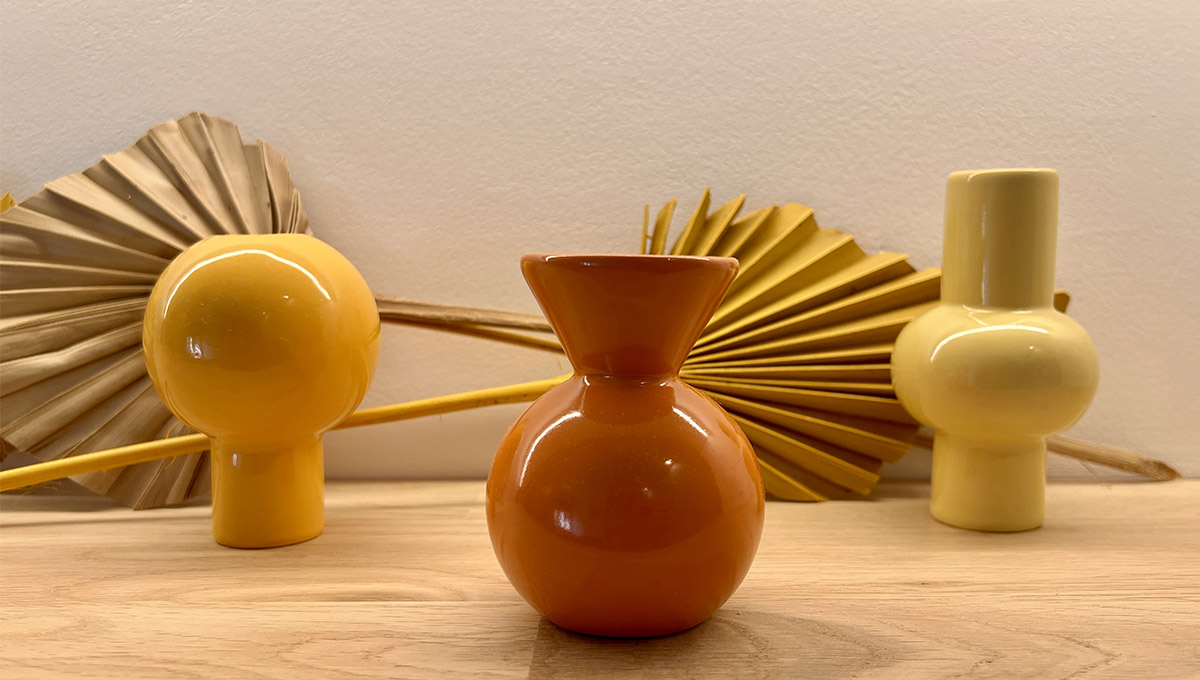 Trois vases décoratifs jaunes et orange accompagnés de feuilles de palmier séchées dans le gîte La Réserve