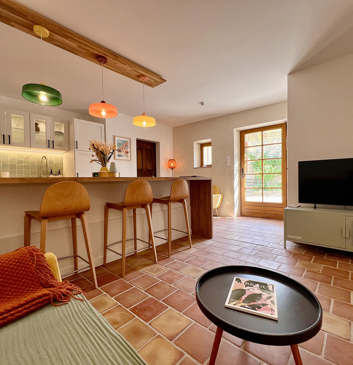 Séjour du gîte La Réserve à Sabran, avec cuisine ouverte, bar en bois, coin salon et sol en terre cuite